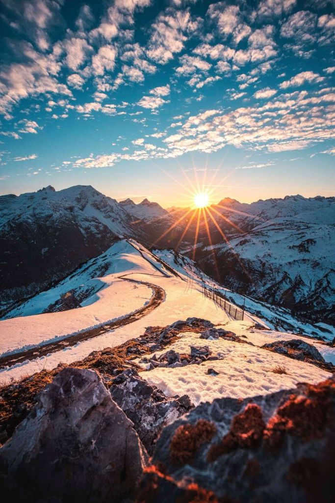 Sentiero tortuoso sotto il sole di montagna innevato