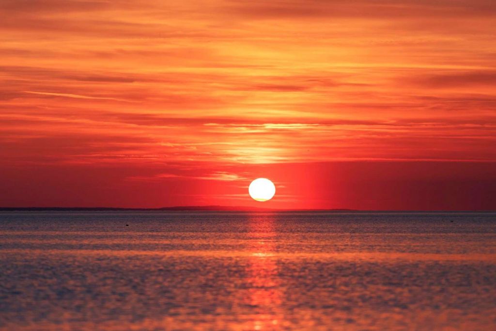 Tramonto infuocato sopra un mare calmo