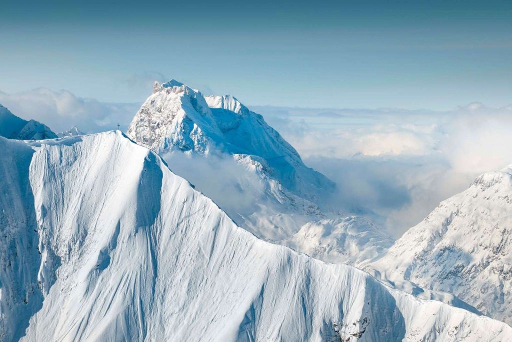 Montagne innevate sopra il manto di nuvole
