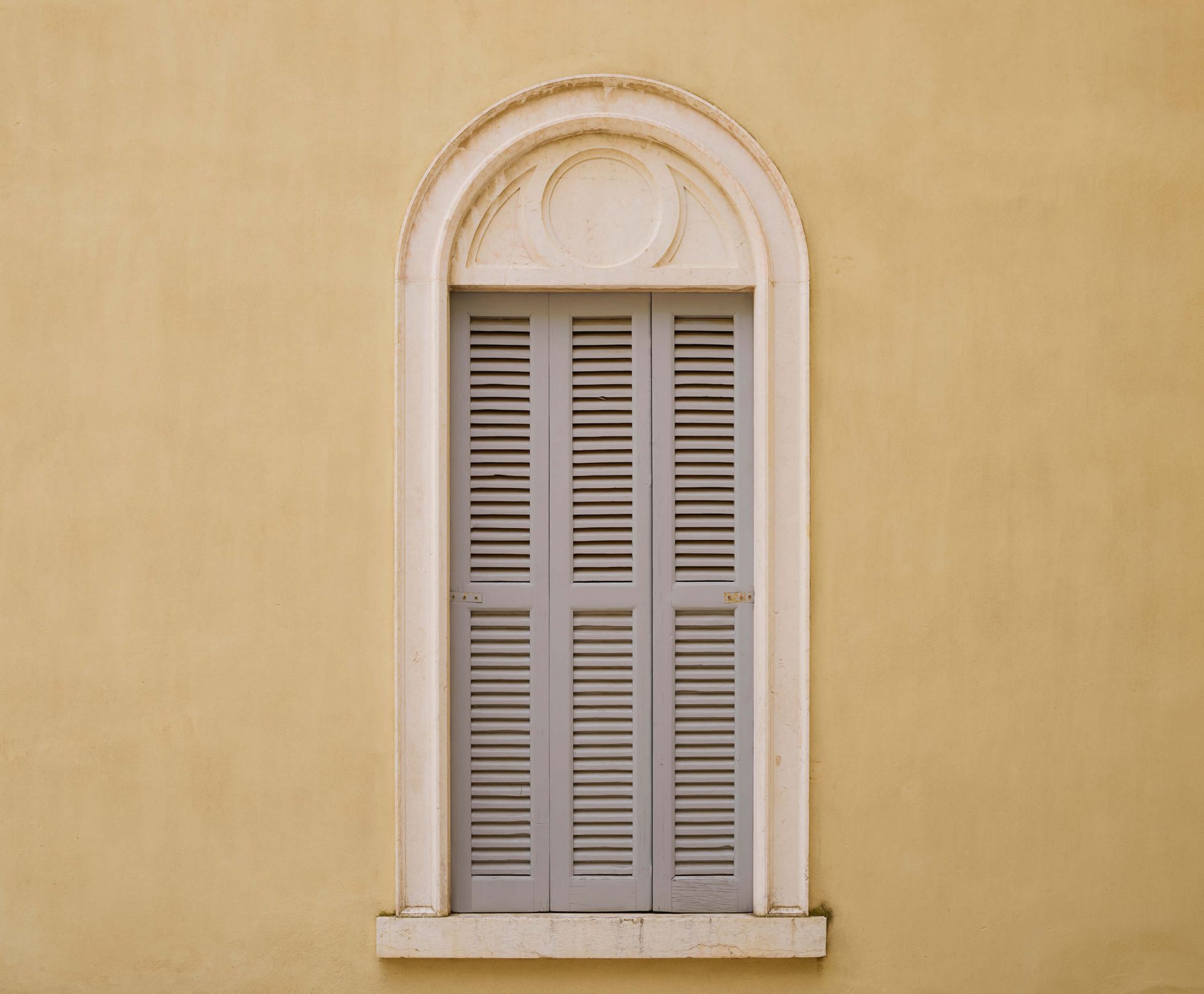 Finestra con persiane in legno su parete gialla