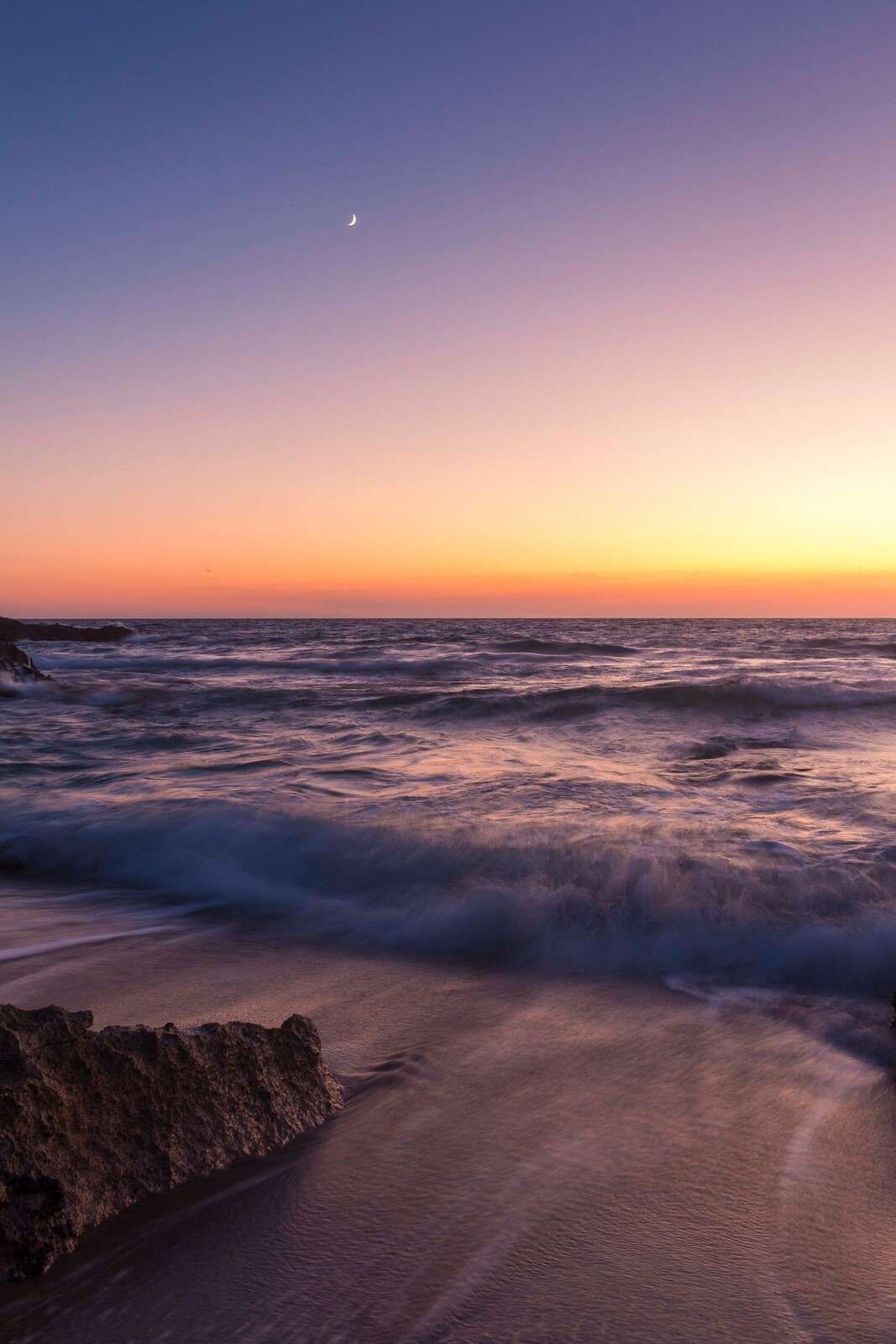 Luce della luna sopra le onde viola al tramonto