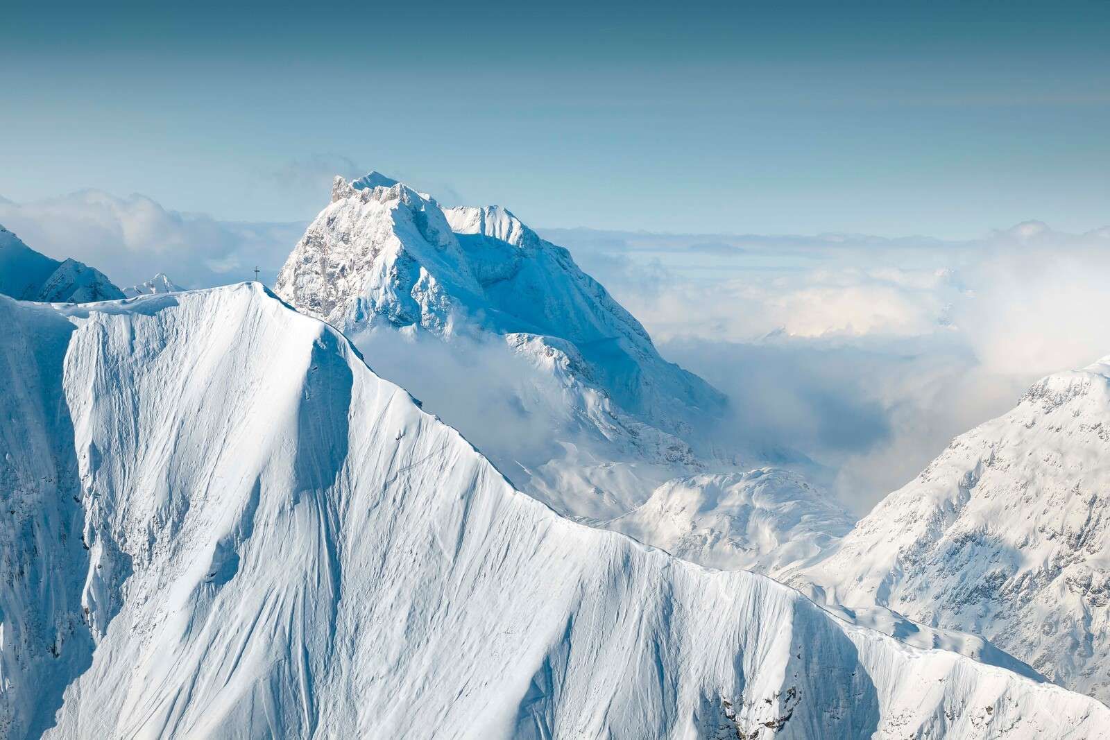 Montagne innevate sopra il manto di nuvole